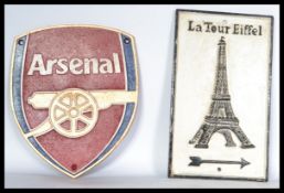 A pair of cast metal plaques for Arsenal football club and the other for the Eiffel tower. Highest