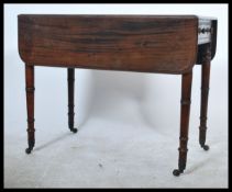 An early 19th century Georgian Pembroke table raised on ring turned legs with brass castors having