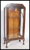 A vintage early 20th century oak cased single glazed door display cabinet raised on cabriole legs on