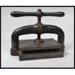 A Victorian 19th century ebonised cast iron and Gunmetal book press with screw and large handle.
