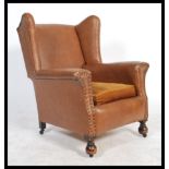 An Edwardian early 20th century club armchair being raised on turned legs with castors and