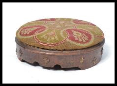 A 19th century Georgian wooden footstool having brass fluer de lis decoration with tapestry topped
