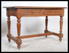 An early 20th century provincial oak writing table desk being raised on reeded turned legs united by
