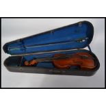A 19th / 20th century cased violin with a two-part back, scrolled end and boxwood pegs , mother of
