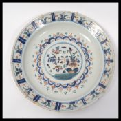 An early 18th century polychrome Delft charger plate having three colour hand painted decoration