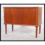 A 1970's retro Danish inspired teak wood tambour fronted record cabinet. The twin roll front doors