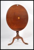 A George III mahogany inlaid tilt top wine table, the circular top above a bird cage mount, raised