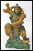 A large 19th century Chinese ceramic figure of a warrior with green and brown colouring. The man
