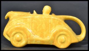 A Sadler art Deco ceramic novelty teapot modelled as a racing car and driver in mottled yellow