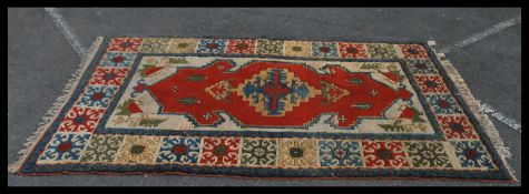 A very large 20th Century floor rug on red ground having a central medallion with geometric