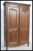 A 19th century carved oak French armoire of smaller proportions being raised on stub legs with