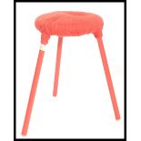 A vintage retro 20th century tripod stool raised on red painted tapering legs with woolen red