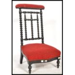 A 19th Century French ebonised and upholstered bobbin turned prie dieu chair, raised on turned