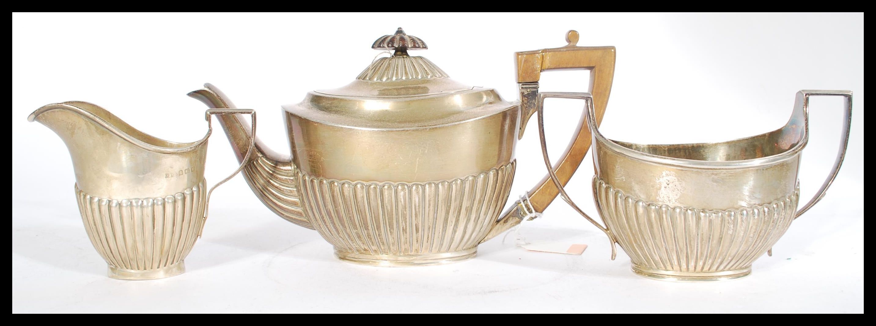 A silver hallmarked three piece boat shaped matched tea service having a part fluted gadrooned