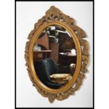 A vintage gilt surround oval wall mirror having an inset bevelled glass plate. The frame decorated
