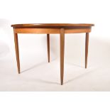 A retro 1960's teak wood G-Plan extending dining table of round form raised on tapering legs