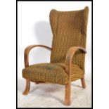 A retro mid century bentwood armchair being raised on splayed legs with wingback rest and shaped