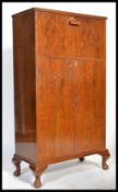 A 1930's Art Deco walnut cocktail cabinet being raised on stub cabriole legs with cupboards under an