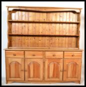 A 20th century country pine antique style dresser having cupboards and drawers to the base with a