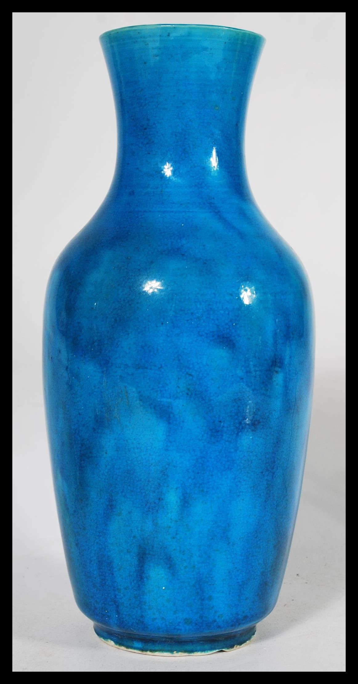 A 19th century Chinese monochrome bottle vase, glazed in merging tones of vibrant blue, elongated