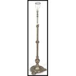 A polished metal rococo revival standard lamp being raised on a terraced base with pad feet and a