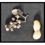 An unusual enamel pill pot box in the form of a peanut along with a silver white metal grapes and
