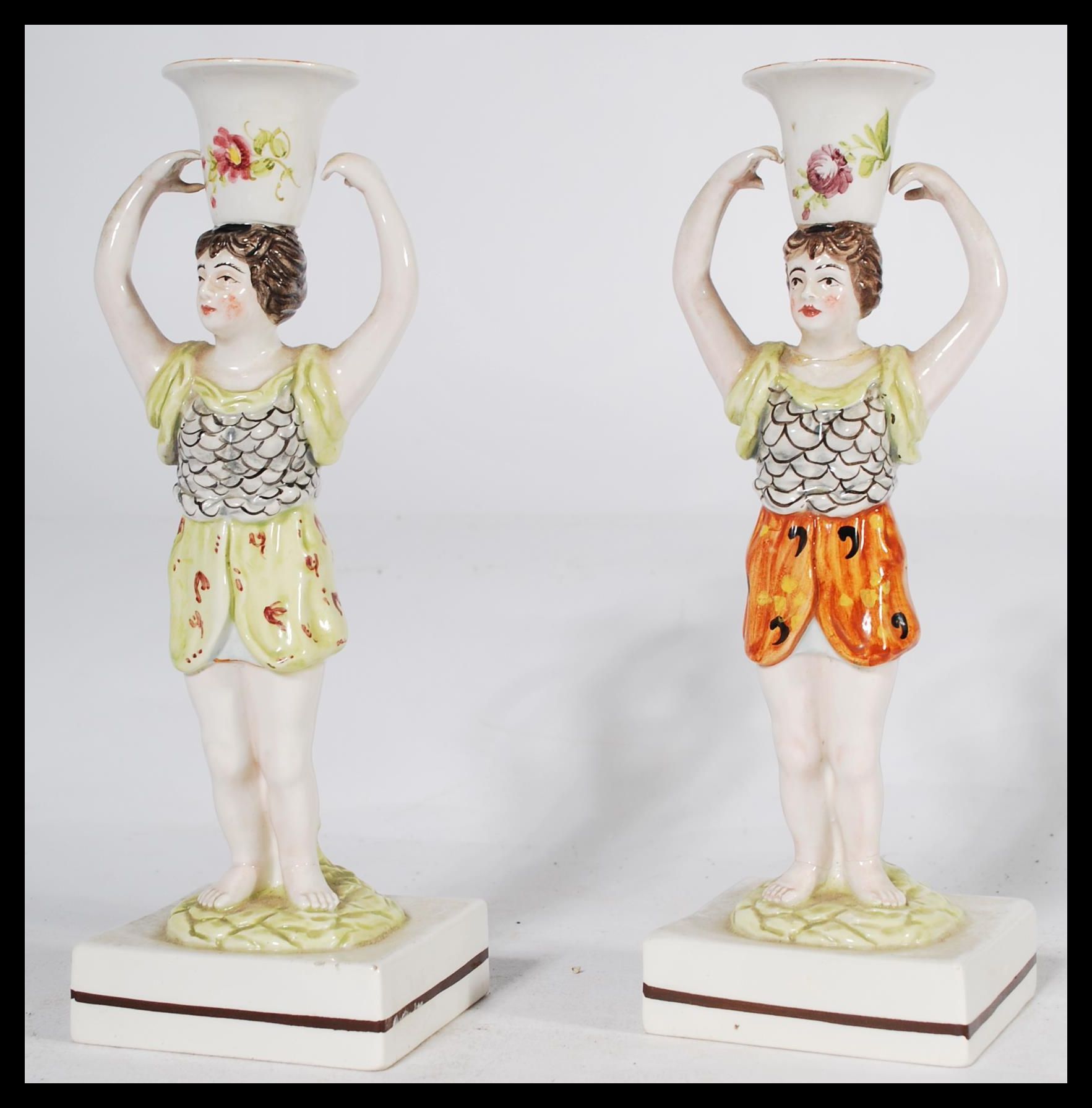A pair of 19th century Staffordshire figural candlestick holders raised on square bases in the