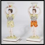 A pair of 19th century Staffordshire figural candlestick holders raised on square bases in the