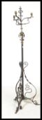 A 20th Century Arts and Crafts style telescopic wrought iron scroll work standard lamp, raised on