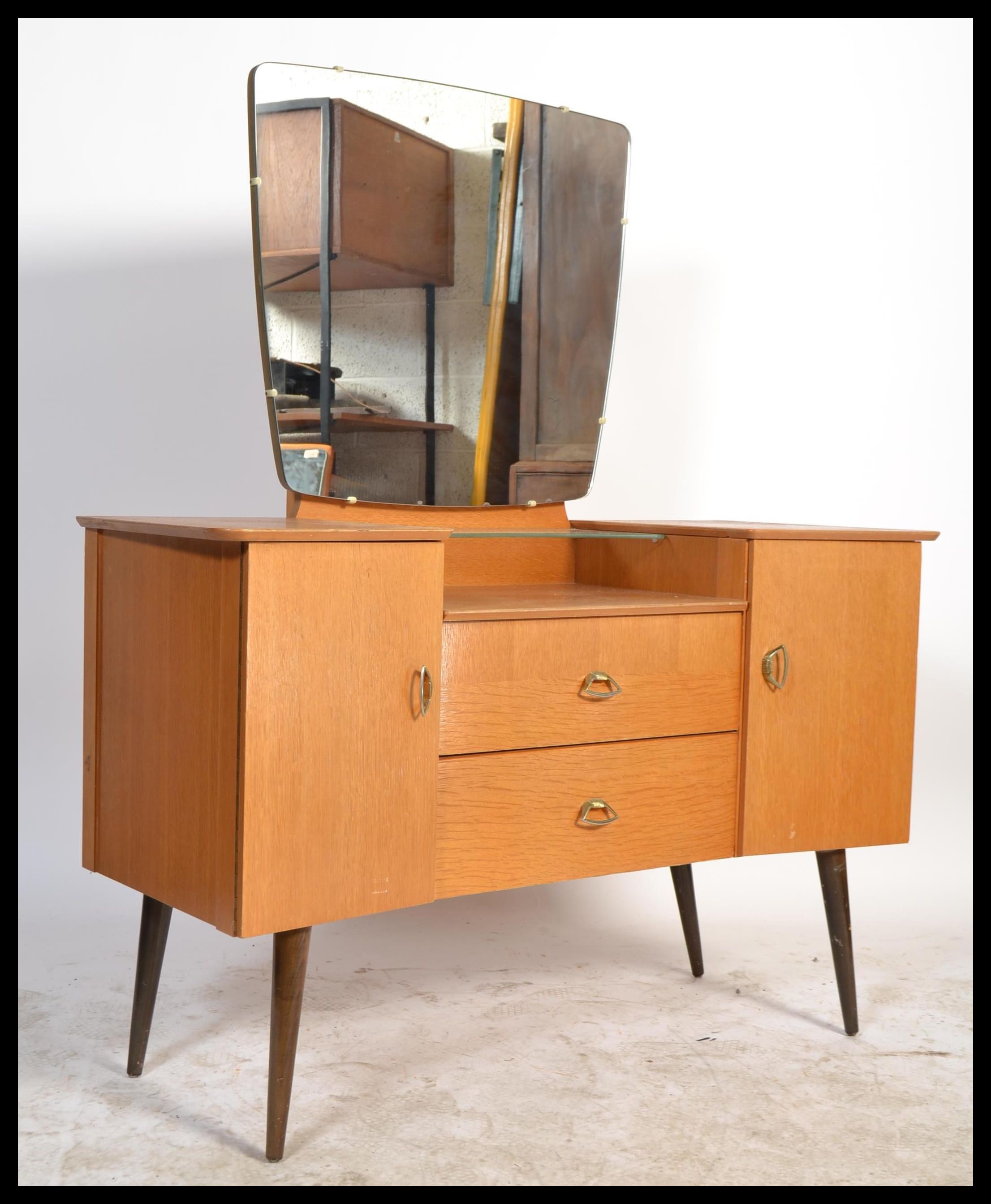 A 1960's retro oak drop centre dressing table being raised on tapering legs with a large mirror of