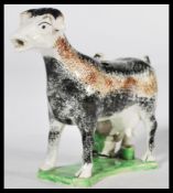 An early C19th Staffordshire pearlware cow creamer, shaped base with milk maid milking into a