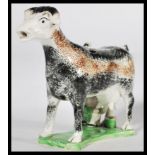 An early C19th Staffordshire pearlware cow creamer, shaped base with milk maid milking into a