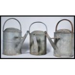 A collection of three vintage 20th Century galvanised metal watering cans, some with impressed