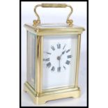 An early 20th century gilt brass French carriage clock having a white enamel face with Roman numeral