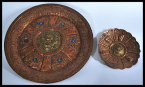 A pair of early to mid 20th Century copper wall chargers of different sizes with temple dogs in
