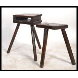 Two early 20th century oak ebonised milking stools on tripod legs with panel seats. One having