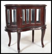 A 20th century antique style hardwood kidney cabinet bijouterie having bevelled glass panels and