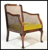 An Edwardian mahogany bergere library armchair / chair having green velour panel seat with caned