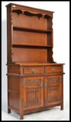 A Jaycee Jacobean revival oak dresser being raised on stile legs with linen fold cupboard doors