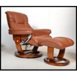 A Stressless style brown leather reclining armchair and matching ottoman raised on a faux wood