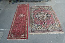 A 20th century long Persian runner rug with central red ground and geometric borders and medallions.