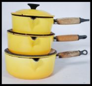 A graduating set of three French Le Creuset lidded cooking pans in an unusual yellow enamel