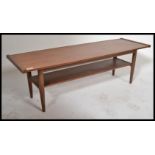 A retro 20th Century teak wood surfboard style coffee table raised on shaped supports with a solid