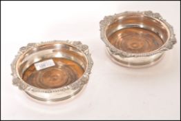 A pair of silver plated wine coasters having gadro