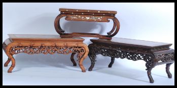 A pair of Chinese hardwood marble tea tables being raised on faux bamboo supports with heavily