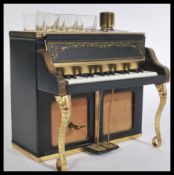 A vintage 20th century drinks compendium decanter and six glass set within a musical piano case.