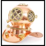 A vintage copper and brass desktop model of an antique deep sea divers helmet with clear acrylic