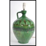 A vintage mid 20th century studio pottery lamp having a green glaze finish. The lamp of bulbous form