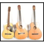 A group of three vintage acoustic six string guitars having shaped hollow bodies with paper labels