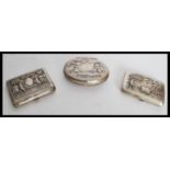 A collection of 3 white metal cigarette cases all pressed in relief with village scenes. One dated